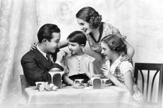 Family at breakfast, 1930s, Happy family at the table, laughing together and enjoying tea time,