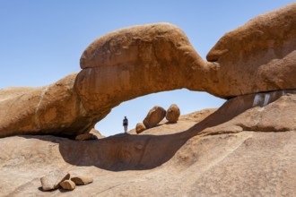 Tourist in a rock arch, round rock formations with stone arch, Pontok Mountains, Great Spitzkoppe,