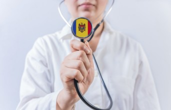 Female doctor holding stethoscope with Moldova flag. National health system of Moldova