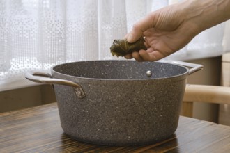 A person prepares traditional dolma by carefully placing a stuffed grape leaf into a pot on a