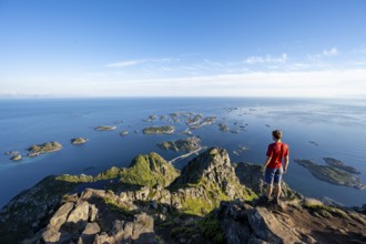 View of numerous small rocky islands with houses, mountaineers on the summit of Festvågtind, view