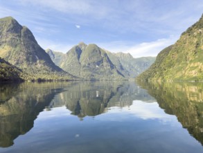Mountains with reflections in the water against a blue sky in Doubtful Sound, South Island, New