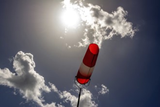 A colorful windsock hangs from a tall pole, clearly indicating wind direction. The bright sky is