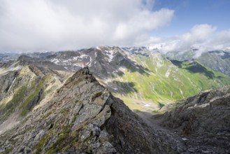 Mountaineer on a steep rocky ridge, on the summit of the Lasörling, view of the mountain panorama