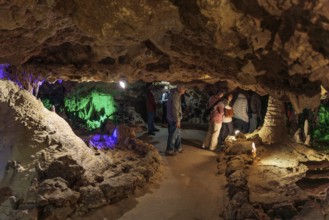 Tourists walking past limestone rock formations in a cave at Florida Caverns State Park in the