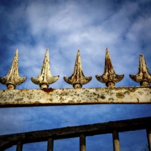 Close-up view of an ornamental iron fence featuring pointed spikes, showcasing rust and weathering