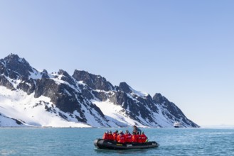 Zodiac in front of mountain range with snow, sea, Fugelfjorden, Spitsbergen, Svalbard