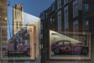 Reflections in a shop window, pink cars and church tower, Portobello Road, Notting Hill, London,