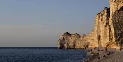 People on the beach, pebble beach, rock arch Falaise or Porte d'Amont, Étretat, sea, steep coast,