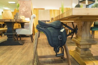 A saddle lies on a wooden chair in a furniture shop, surrounded by rustic woodwork, Sindelfingen,