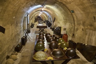 A tunnel with historical helmets displayed on a table, illuminated by warm light, steel helmets,