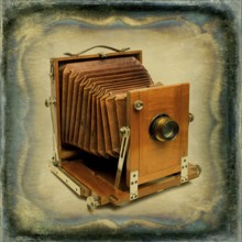 Old wooden camera with bellows displayed against a textured vintage background, showcasing