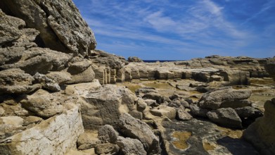 Rough rocky terrain with a view of the sea in sunny weather, Oasis Beach, east coast of Rhodes,