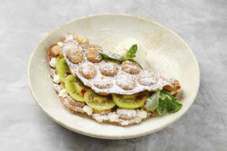 A delightful dessert showcases a fluffy shell filled with fresh kiwi slices and whipped cream,