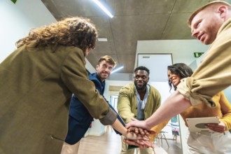 Five businesspeople joining hands together in office, showing their unity and cooperation for a