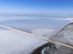 A vast salt lake under a clear blue sky, with simple geometric lines and footbridge, aerial view,