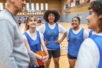 Happy multi ethnic female basketball players listening to coach instructions during training in a