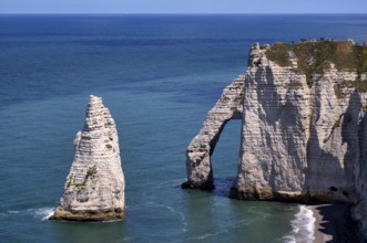 Tourists, visitors on rock arch Falaise or Porte d'Aval and rock needle Aiguille, Étretat, sea,