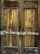 Close-up view reveals a weathered wooden door adorned with intricate patterns and robust metal