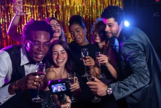 Group of cheerful multi ethnic friends taking selfie with action camera while enjoying champagne