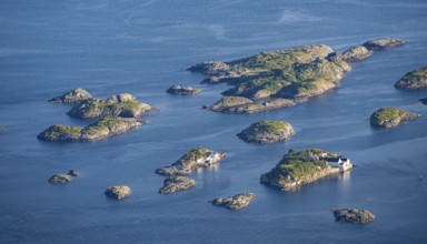 Small rocky islands with individual houses in the sea, archipelago islands, near Henningsvær,
