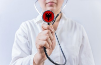 Female doctor holding stethoscope with Albania flag. National health system of Albania