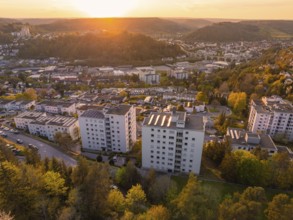 Housing estate with tall buildings and green surroundings at sunset, with a view of the town and