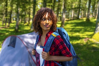 Young woman with a backpack enjoying the tranquility of a forest, discovering nature while camping