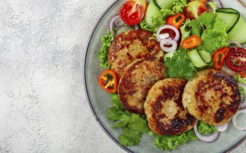 Fried chicken cutlets, minced chicken, with vegetables, on gray, with vegetable salad, top view,