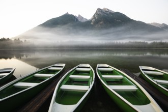 Magical sunrise with fog at Hintersee near Ramsau in Berchtesgadener Land. Boats in the foreground