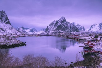 Fishermen's Village in front of snowy mountain range at the coastline in winter, Lofoten, Norway