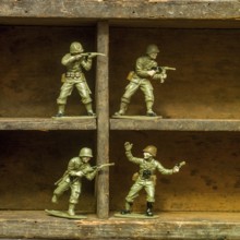 A set of classic plastic toy soldiers arranged on a wooden shelf, displaying soldiers in various