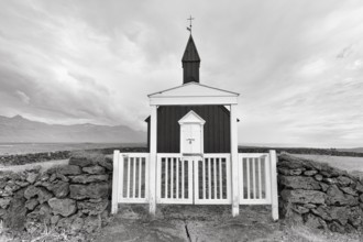 Traditional black church with white wooden door and stone wall, wooden church Budakirkja,
