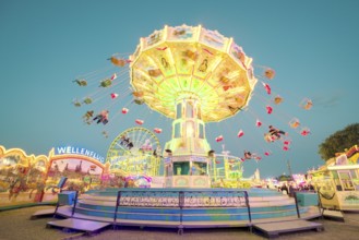 A brightly lit chain carousel turns at a daytime fair, Chain carousel, Spring festival, Cannstatter
