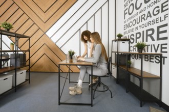 Two women are collaborating on a project in a stylish, modern office designed for a startup focused