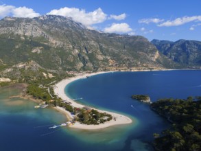 Aerial view of a picturesque coastline with sandy beach, mountains and clear water under a blue