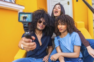 Three latin friends filming a vlog using a gimbal and action camera, enjoying laughter and smiles