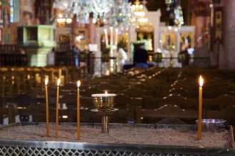 Burning candles on a sand container in an illuminated church with blurred surroundings, Church of