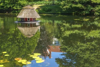 Floating duck breeding house with thatched roof, serose leaves, water reflection with villa from