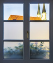 View through a closed window to the collegiate parish church of St Philip and St James, place of