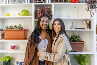 Two happy female friends are smiling and embracing in a plant shop, surrounded by shelves filled