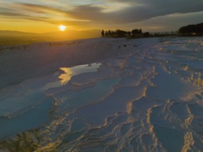 Terraced landscape at sunset with reflecting water and dramatic sky, aerial view, sinter terraces,