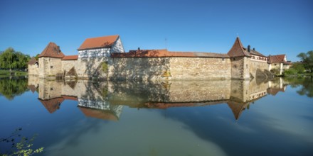 The town wall with defence towers and half-timbered house is reflected in the lake pond,