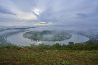 River bend under a cloudy sky and enveloping fog, gentle hills define the scenery, summer, Rhine