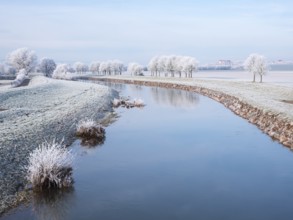 The river Unstrut in the Unstrut valley in winter, fields and trees covered with hoarfrost, behind