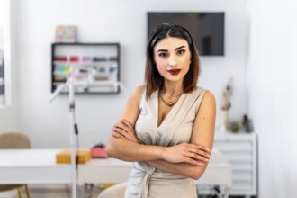 Young female entrepreneur posing with crossed arms in her hair and beauty salon, looking confident