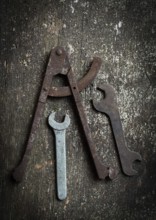 A collection of vintage tools, including a caliper and several wrenches, rests on a rustic wooden