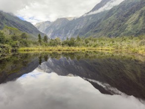 Hiking trail of the Roberts Point Track at Franz Josef Glacier with reflections of mountains in the