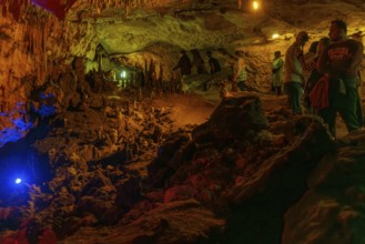 Tourists walking past limestone rock formations in a cave at Florida Caverns State Park in the