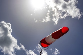 A colorful windsock hangs from a tall pole, clearly indicating wind direction. The bright sky is